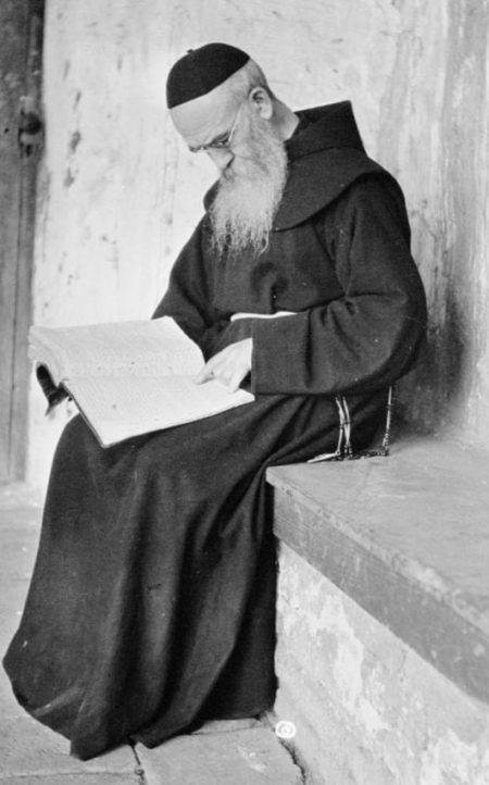 Father Zephyrin Engelhardt reading the original register of San Juan Capistrano on the South Wing, 1920. The register was begun in Father Serra's own handwriting.